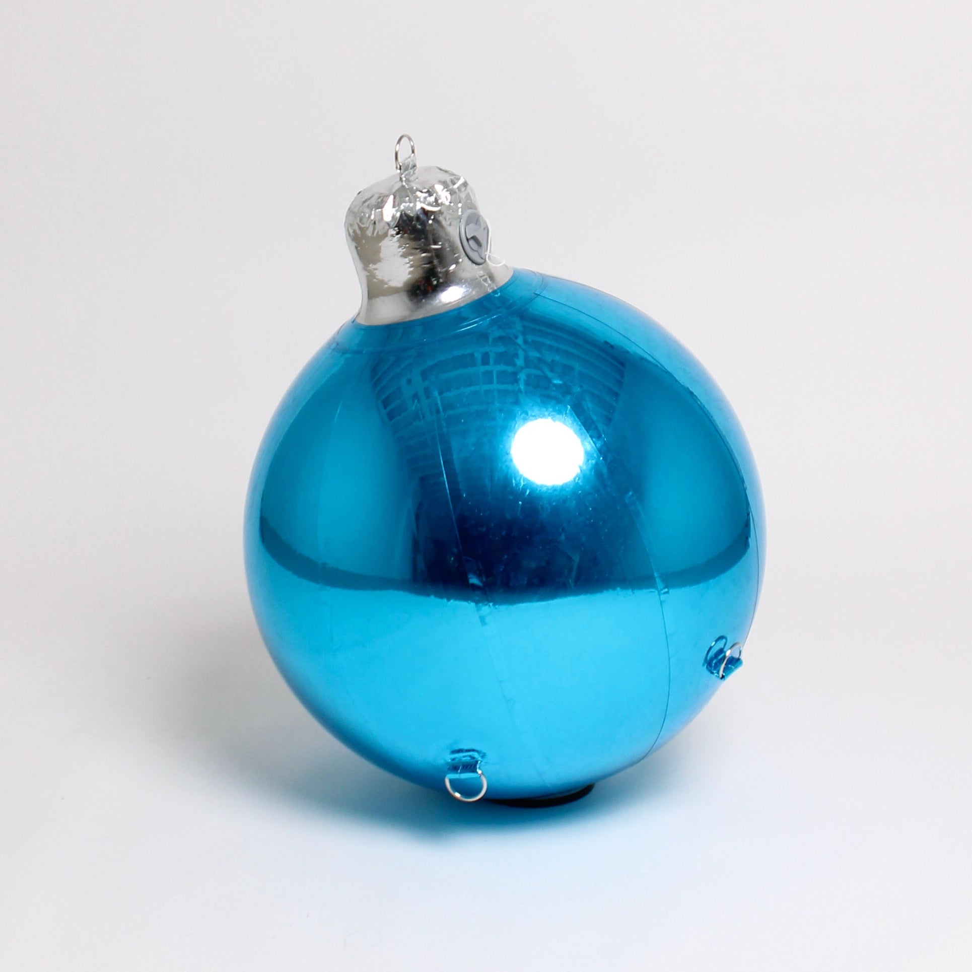 Blue Christmas ornament with silver cap on a white background