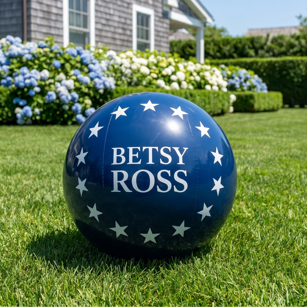 Blue ball with 'Betsy Ross' text on a grassy lawn in front of a house.