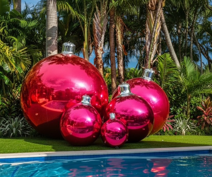 Large pink Christmas ornaments by a pool with palm trees in the background