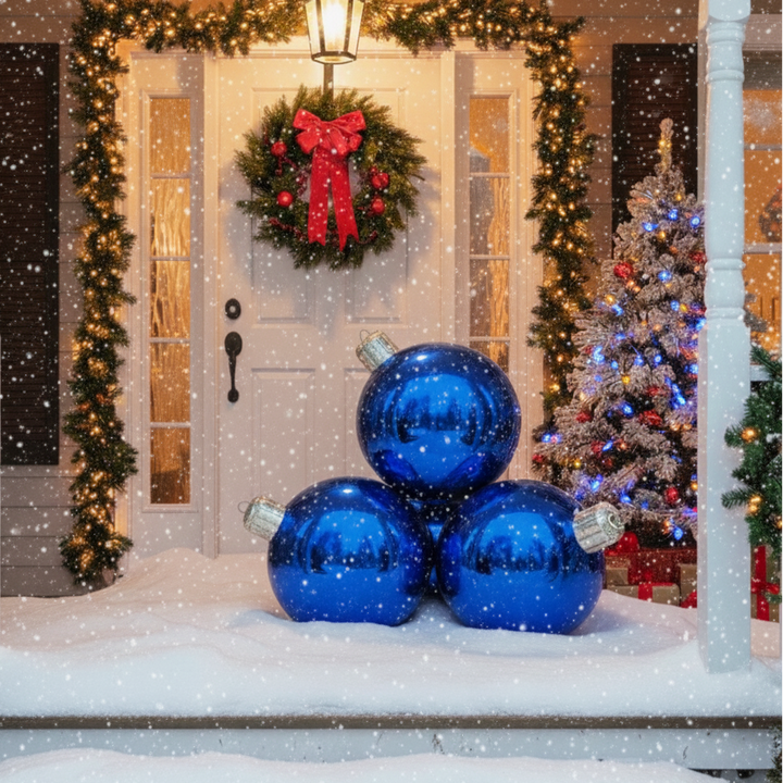 Decorative blue ornaments on a snowy porch with a Christmas tree and wreath in the background.
