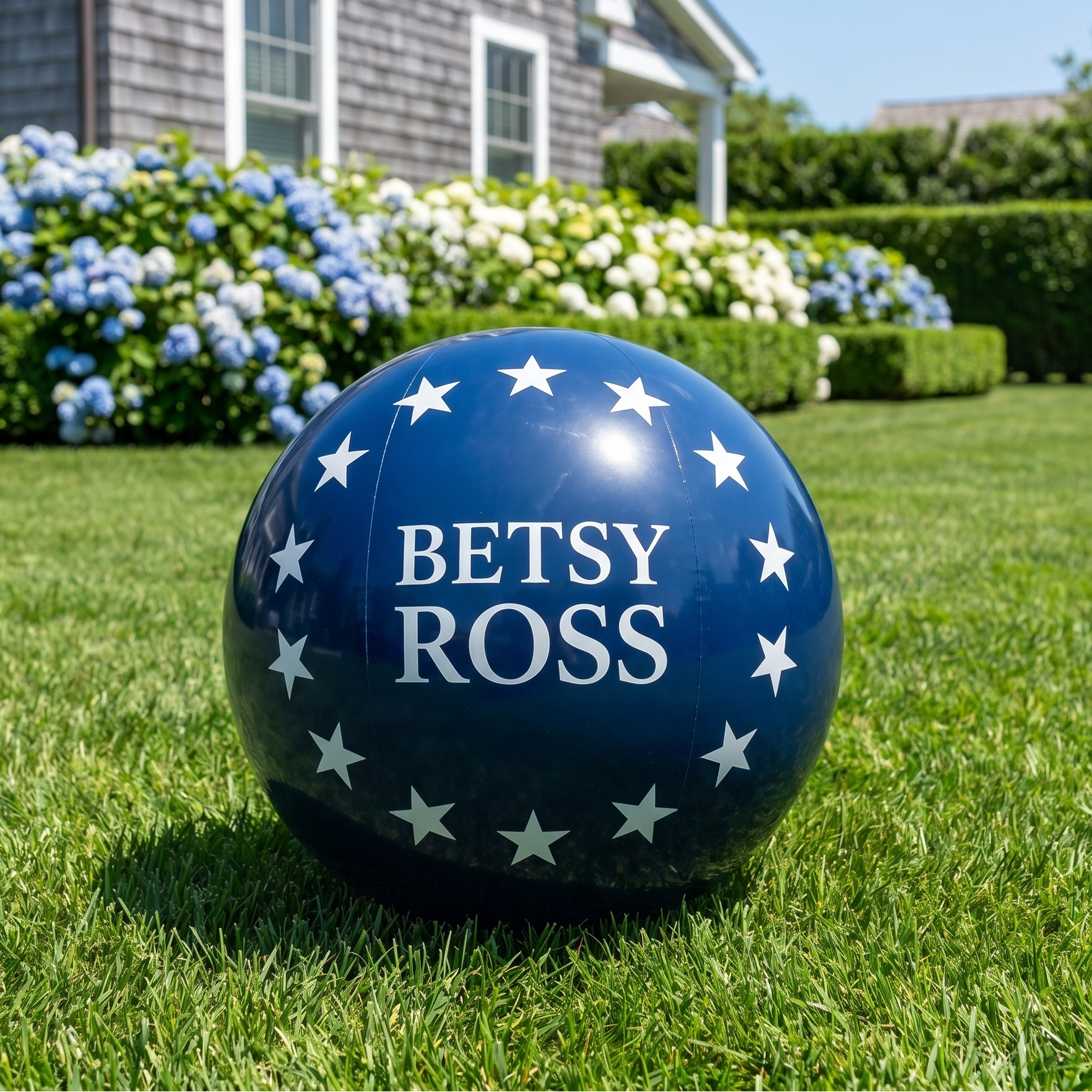 Blue ball with 'Betsy Ross' text on a grassy lawn in front of a house.