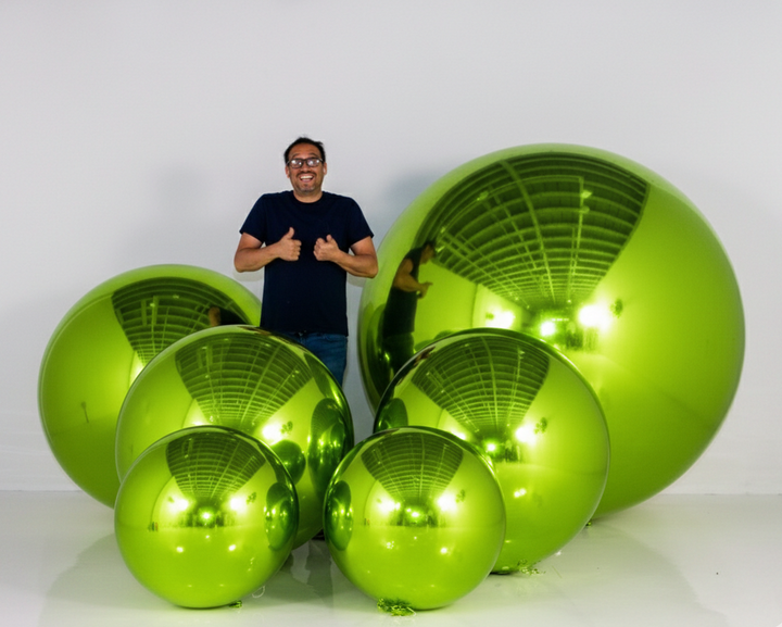 Man standing next to large green metallic spheres on a white background