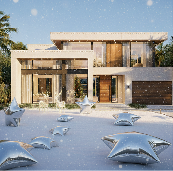 Modern house with decorative silver star sculptures in front on a snowy day.