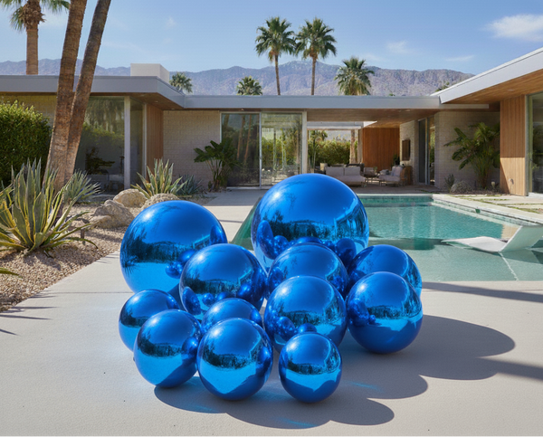 Blue reflective spheres on a patio with a pool and house in the background