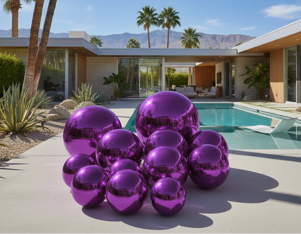 Purple metallic spheres in front of a modern house with a pool and palm trees.